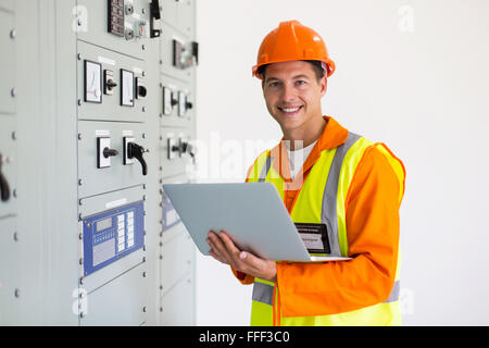 Porträt des jungen Ingenieurs mit Laptop im Kontrollraum Stockfoto