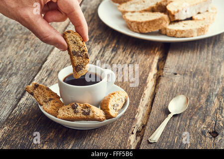 Hand-Dip Cantucci in den Kaffee. Typische italienische cookies Stockfoto