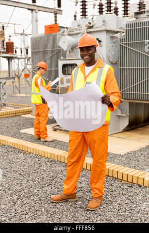 Porträt der schönen afrikanischen Elektro Ingenieur mit Blaupause im Umspannwerk Stockfoto