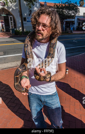 Inhaber eines Schlange drapiert seine kolumbianische Boa Constrictor um den Hals, da er die Schlange für Fußgänger zeigt, Geld zu sammeln. Stockfoto