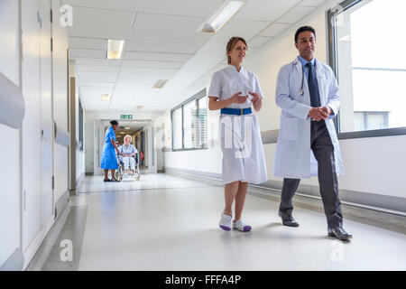 Ältere weibliche Frau Patienten im Rollstuhl sitzend im Krankenhausflur mit Krankenschwestern und Arzt Stockfoto