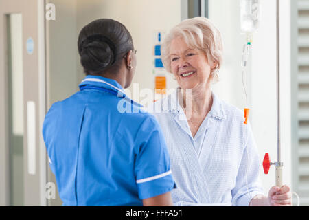 Ältere weibliche Frau Patienten im Krankenhausflur Gespräch mit afroamerikanischen Krankenschwester Stockfoto