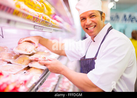 glücklich Metzger Fleischprodukte im Supermarkt zu organisieren Stockfoto