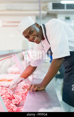 glücklich afroamerikanische Metzger Kommissionierung rohes Fleisch Stockfoto