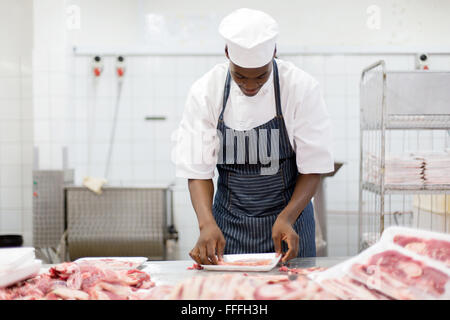 Afrikanische männlichen Metzger Fleischstücke in einem Tray Verpackung Stockfoto