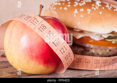 Hamburger und Apfel mit Messgerät Closeup. Diät-Konzept Stockfoto