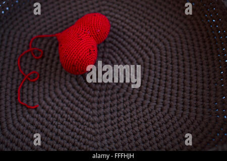 rotes gestricktes Herz gestrickte Gewebe braunen Hintergrund, stricken, stricken Stockfoto