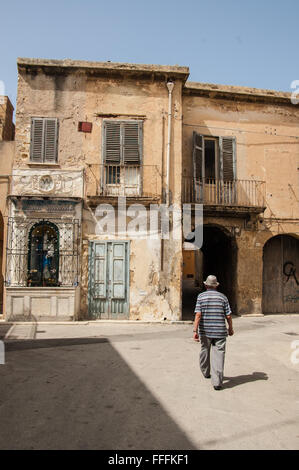 Alten italienischen Mann unter heruntergekommene Häuser in der mittelalterlichen Viertel von Marsala, Sizilien, Italien. Stockfoto