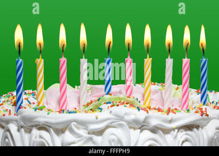 Geburtstagstorte mit bunten Kerzen auf grünem Hintergrund. Stockfoto