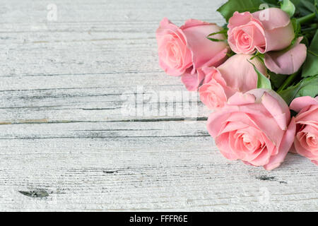 Vintage-Hintergrund / Postkarte / Grusskarte. Rosa Rosen auf weißem strukturierten hölzernen Hintergrund. Textfreiraum, Ansicht von oben Stockfoto