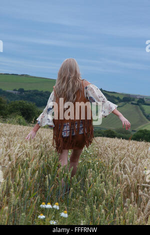 Rückseite des Mädchens zu Fuß in ein Weizenfeld mit dramatischen Stimmungsvoller Himmel hinter Stockfoto