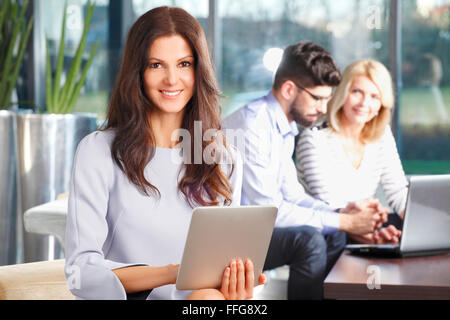 Bild von attraktiven mittleren Alters Geschäftsfrau hält digitale Tablet sitzend bei Geschäftstreffen. Geschäftsleute Stockfoto