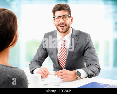 Bild der junge Geschäftsmann sitzt am Schreibtisch vor dem Computer und tun Job-Interview mit weiblichen Mitarbeiter. Stockfoto