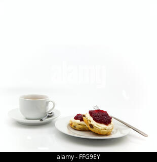 Cream Tea - Scones mit Marmelade und Sahne, serviert mit einer Tasse Tee auf weißem Hintergrund Stockfoto