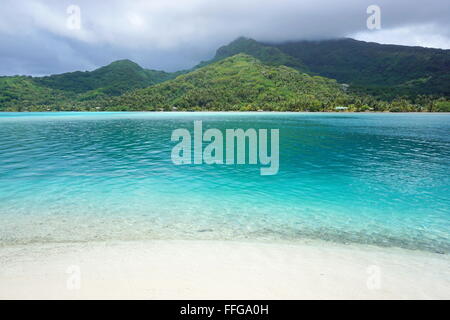 Landschaft von Huahine Island gesehen von einem weißen Sandstrand mit türkisfarbenem Wasser im Vordergrund, Pazifik, Französisch-Polynesien Stockfoto