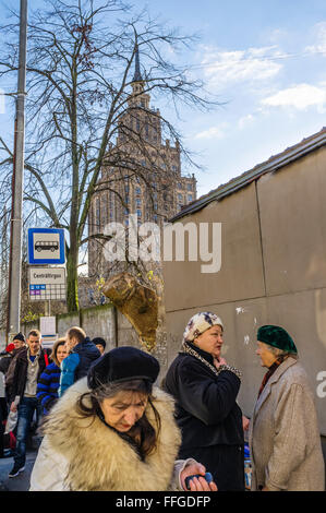 Lettische Frauen auf einen israelischen Bus stop mit der Akademie der Wissenschaften sowjetischen Gebäude im Hintergrund. Riga, Lettland Stockfoto