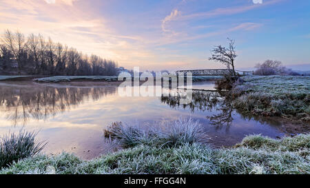 Kalten frostigen Morgen, Blick über den Fluss Stour mit Steg auf den Wiesen Sudbury, Suffolk, England. Stockfoto