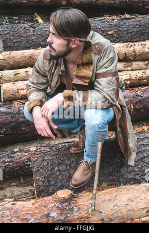 Junge Männer auf Baumstämmen im Wald. Leder und jeans Stockfoto