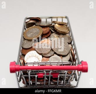 Kleiner Supermarkt Einkaufswagen mit Münzen. Cost Of Living-Konzept Stockfoto