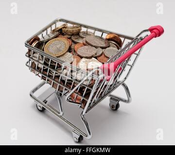 Kleiner Supermarkt Einkaufswagen mit Münzen. Cost Of Living-Konzept Stockfoto