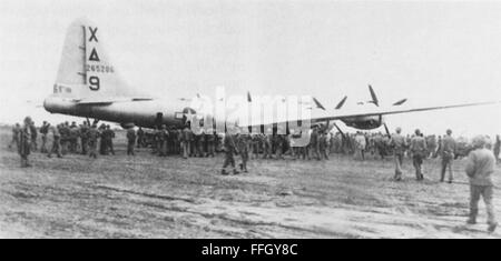 "Dinah Might," die erste verkrüppelten b-29 Superfortress zu einer Notlandung auf Iwo Jima während des zweiten Weltkriegs, ist umgeben von Marines und Seabees am 4. März 1945. Stockfoto