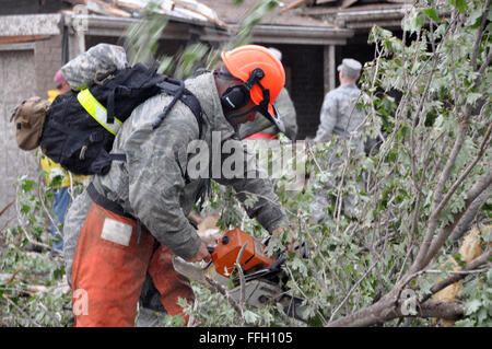 Ein militärisches Mitglied schneidet Bäume, die auf Häusern gesenkt wurden, nachdem ein Tornado die Stadt Moore, Okla. 20. Mai 2013 getroffen. Stockfoto