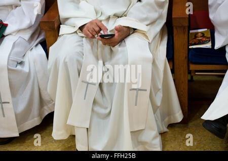 Ehemaliger Kaplan (Oberstleutnant) Robert Bruno liest Verse der Bibel auf eine Anwendung in seinem Telefon während eines Gottesdienstes Morgengebet in der Casa O'Toole Kapelle auf dem Hochschulcampus. Stockfoto