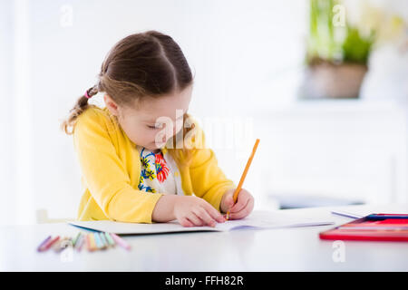 Niedliche kleine Mädchen Hausaufgaben machen, ein Buch zu lesen, Malvorlagen, schreiben und malen. Kinder malen. Kinder ziehen. Stockfoto