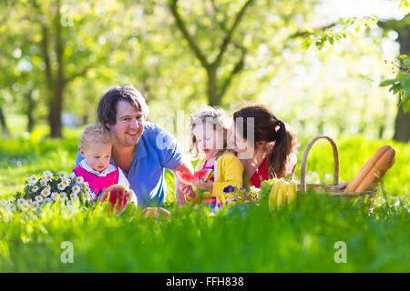 Familie mit Kindern Picknick im Frühlingsgarten. Eltern und Kinder Spaß beim Mittagessen im Freien im Sommerpark. Stockfoto