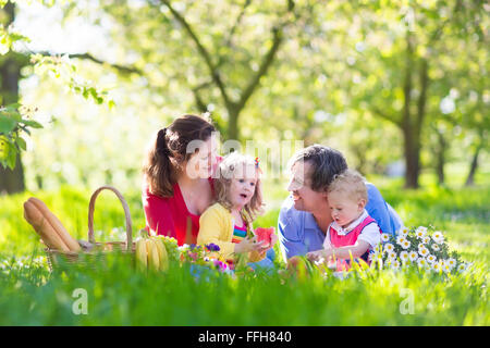Familie mit Kindern Picknick im Frühlingsgarten. Eltern und Kinder Spaß beim Mittagessen im Freien im Sommerpark. Stockfoto