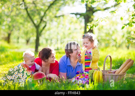 Familie mit Kindern Picknick im Frühlingsgarten. Eltern und Kinder Spaß beim Mittagessen im Freien im Sommerpark. Stockfoto