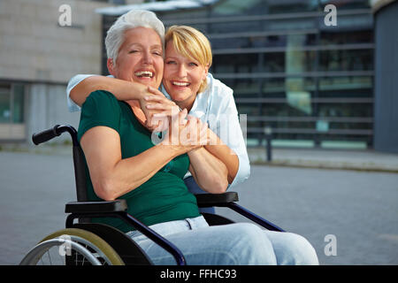 Lächelnd senior Frau im Rollstuhl mit erweiterten Brustschwester deaktiviert Stockfoto