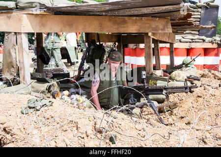 Vietnam Krieg Re-enactment. Von außen uns Holz überdachte Command Bunker am Checkpoint, Marine in Flake Jacket Prüfung M60 Maschinengewehr Stockfoto