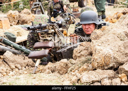 Zweiten Weltkrieg Re-enactment. Zwei Waffen-SS-Männer in der Tarnung einheitliche, hinter einem Maschinengewehr mit Zylinder in Richtung Betrachter. Close-up. Stockfoto