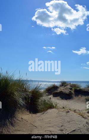 grasbewachsenen Sanddünen und eine glitzernde Meer in Camber Sands in Sussex, England, UK Stockfoto
