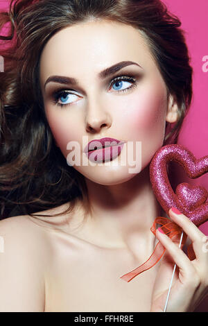 Gesicht des Mädchens. Fest. Herz in den Händen. Rosa Make-up. Glamour. Stockfoto