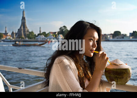 Romantisch schöne Mädchen in einem Boot in der Nähe von Wat Arun Tempel und Chao Praya River. Trinken ein Coconout. Chao Phraya Touristenboot. Die BTS-S Stockfoto