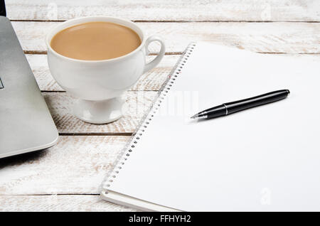 Tasse Kaffee und Laptop auf hölzernen Bürotisch. Stock Bild. Stockfoto