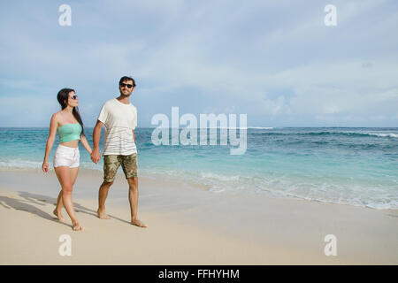 Glückliche junge Paar Hand in Hand am Strand spazieren.  Stock Bild Stockfoto