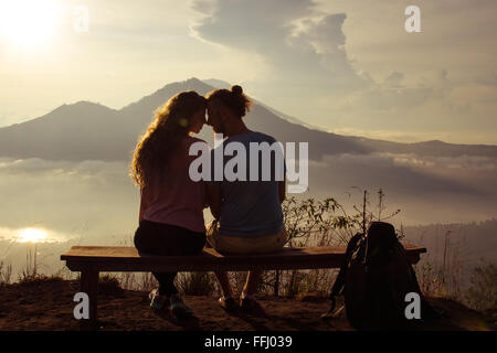 Rückansicht eines liebenden Paares genießen den Sonnenuntergang in der Sonne am Gipfel des Berges. Stock Bild. Stockfoto