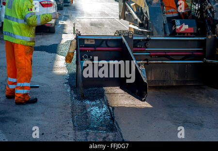 Arbeiter im Straßen-und Wegebau Asphalt Fertiger Maschine in Betrieb und Reparatur arbeiten Stockfoto