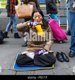 London, UK. 14. Februar 2016. Eine Frau in Londons Chinatown meditiert unter den Silvester Feier Massen als Bestandteil eines Protestes und Petition zum Stopp Organraub in China. Festlichkeiten in Chinal Stadt, Soho und Trafalgar Square zu feiern das chinesische Neujahr, Jahr des Affen, die am 8. Februar begann. Stockfoto