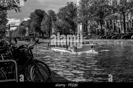 Kanalboot in Amsterdam. Schwarzweißansicht auf Kreuzfahrt Boot am Nieuwe Herengracht Kanal in Amsterdam. Stockfoto