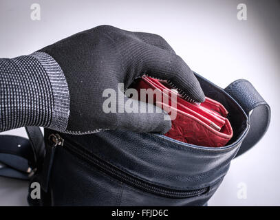 Einbrecher Typ Dieb tragen einen schwarzen Handschuh versucht, ein Verbrechen zu begehen, durch den Diebstahl eines Weibes rotem Leder Geldbörse aus ihr unbeaufsichtigt Stockfoto