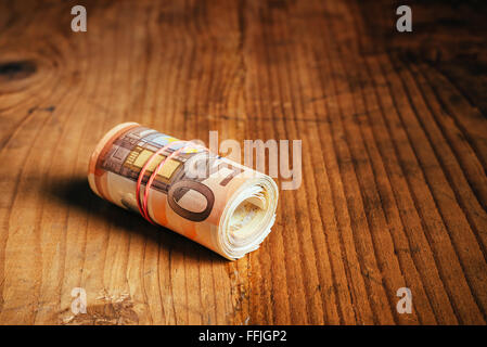 Konzept Geld sparen bares Geld mit Gummiband auf hölzernen Schreibtisch, fünfzig Euro Banknoten persönliche Haushaltsbudget Stack aufgerollt Stockfoto