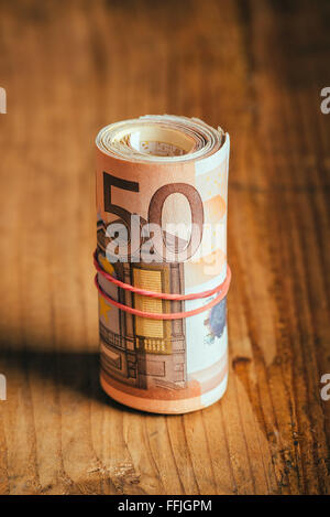 Konzept Geld sparen bares Geld mit Gummiband auf hölzernen Schreibtisch, fünfzig Euro Banknoten persönliche Haushaltsbudget Stack aufgerollt Stockfoto
