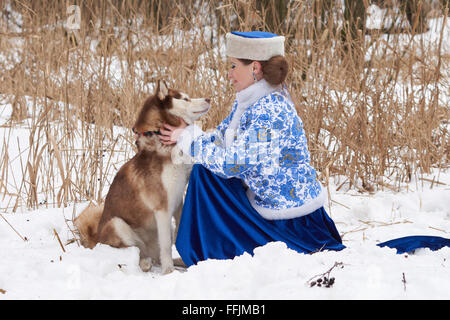 Junge Russin in traditionellen Winterkleidung mit Siberian Husky Stockfoto