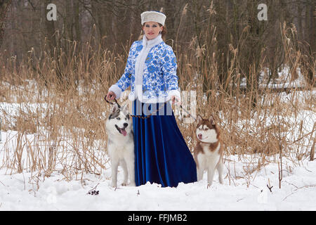 Junge Russin in traditionellen Winterkleidung mit zwei Siberian Huskies Stockfoto