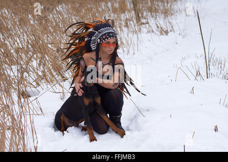 Mädchen in Indianer Kopfschmuck mit Doderman Pinscher Stockfoto