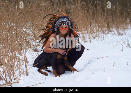 Mädchen in Indianer Kopfschmuck mit Doderman Pinscher Stockfoto